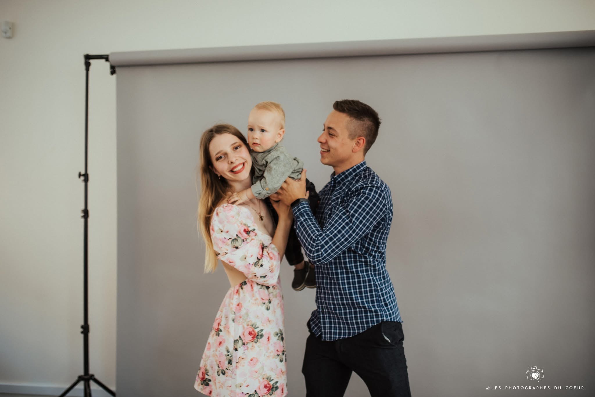 Portrait d’une famille avec son enfant devant un fond de studio.